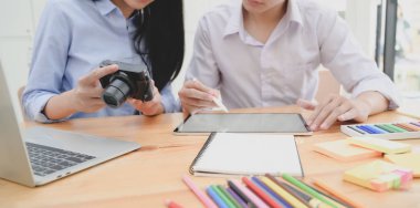 Genç profesyonel tasarımcı ekibi tablet ve kamera kullanırken projelerini tartışıyor