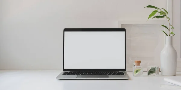 Mock up laptop computer in minimal workspace with copy space and ceramic vase decorations