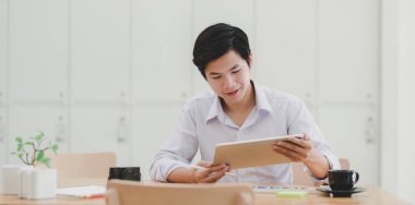 Genç profesyonel erkek tasarımcı projesini iş yerinde tabletle planlıyor.