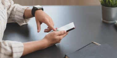 Ofisindeki boş ekran akıllı telefona dokunan genç profesyonel iş kadınının yakın plan görüntüsü. 