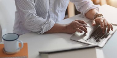 Modern ofisteki projesi üzerinde çalışırken dizüstü bilgisayarında daktilo yazan profesyonel işadamının yakın görüntüsü 