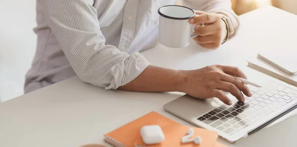 Empresario profesional escribiendo en el ordenador portátil mientras bebe una taza de café —  Fotos de Stock