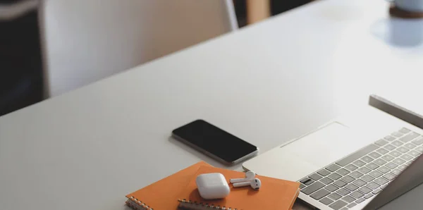Vista de primer plano del lugar de trabajo moderno con teléfonos inteligentes y suministros de oficina en la mesa de madera blanca —  Fotos de Stock
