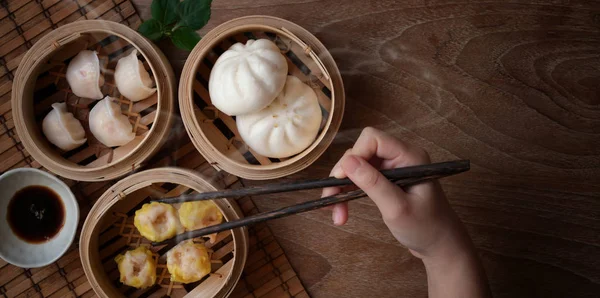 Overhead shot of woman eating Chinese steamed dumpling and steamed pork bun — Stock Photo, Image