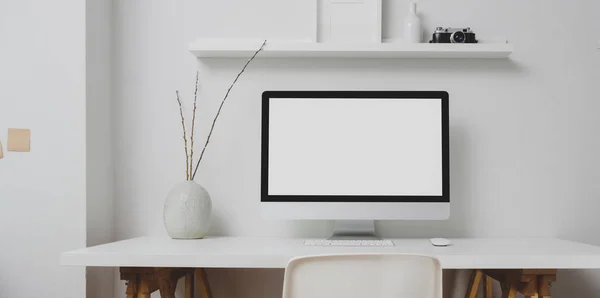 Modern workspace with blank screen desktop computer and decorations on white table and white wall background