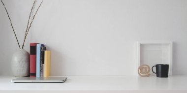 Kopya alanı olan en az çalışma alanı, beyaz ahşap masa ve beyaz duvar arkaplanındaki çerçeve ve ofis malzemelerini düzenle 