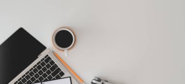 Laptop bilgisayarı, ofis malzemeleri ve beyaz masa üzerindeki kahve fincanı ile modern çalışma alanının en üst görüntüsü 