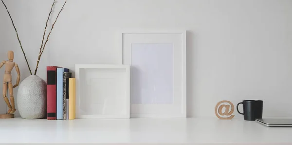 Espacio de trabajo mínimo con maqueta de marco y suministros de oficina sobre mesa de madera blanca y fondo de pared blanco —  Fotos de Stock