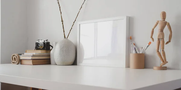 Ruang kerja minimal dengan kerangka dan perlengkapan kantor tiruan di atas meja kayu putih dan latar belakang dinding putih — Stok Foto