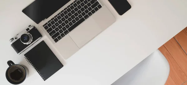 Ovanifrån av minimal arbetsplats med bärbar dator, kamera och kontorsmaterial på vitt skrivbord — Stockfoto