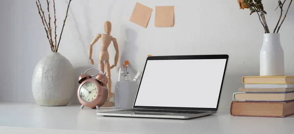 Lugar de trabajo contemporáneo con ordenador portátil de pantalla en blanco abierto, suministros de oficina y decoraciones en la mesa blanca — Foto de Stock