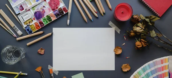 Vista superior del estudio del artista con papel de dibujo, herramientas de pintura, acuarelas y material de oficina —  Fotos de Stock