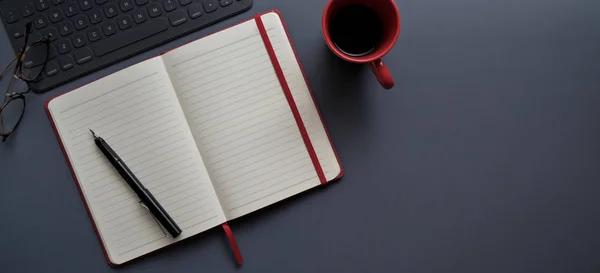 Вид зверху на темне сучасне робоче місце з відкритим ноутбуком та чашкою червоної кави на темно-сірому фоні — стокове фото