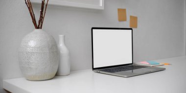 Model dizüstü bilgisayar, kırtasiye, not defteri ve dekorasyonla modern çalışma alanının kırpılmış görüntüsü 