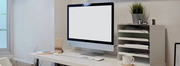 Cropped shot of minimal office desk with mock-up computer , office supplies and decorations on white table