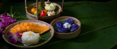 Tahta tepside servis edilen ve muz yapraklarında fotokopi alanı olan birkaç Tayland tatlısının yakın görüntüsü.