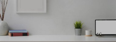 Modern çalışma alanı görünümünü maket dizüstü bilgisayar, kitap, bardak, süsleme ve beyaz masa üzerine kopyalama alanı ile kapat 