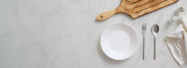 Beyaz tabak, gümüş çatal bıçak, ahşap tepsi ve kopyalama alanı olan mermer yemek masasının üst görüntüsü  