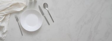 Tabak, çatal bıçak, peçete, baharat şişeleri ve mermer masa üzerindeki fotokopi alanı ile modern yemek masasının üst görüntüsü.  