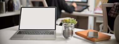 Model dizüstü bilgisayar, kahve fincanı, akıllı telefon ve bulanık ofis arka planındaki not defterleri ile taşınabilir çalışma alanını kapat