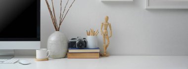 Bilgisayar, fincan, kamera, kırtasiye, dekorasyon ve kopyalama alanı olan modern ofis tablosunun görünümünü kapat