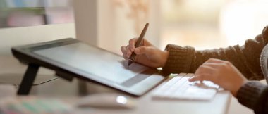 Ofis masasında stilus kalemle tablet çizen kadın grafik tasarımcısının yan görünümü 