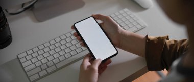 Bilgisayar aygıtıyla çalışılabilirken akıllı telefon kullanan kadın çalışanın görüntüsünü kapat 