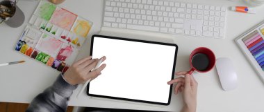 Sahte tabletle çalışan, alet boyayan ve ofis masasında kahve içen kadın ressamların genel görüntüsü. 