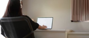 Kadın rahat bir şekilde yatak odasında çalışırken bilgisayar ve kulaklıkla video izlerken çekilmiş görüntüler.