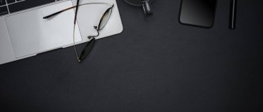 Açık boş defter, gözlük, akıllı telefon, fincan ve kopyalama alanı ile karanlık modern çalışma alanının üst görünümü