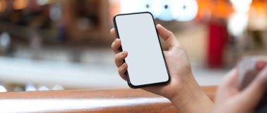 Alışveriş merkezinin balkonunda dikilirken elinde akıllı telefon tutan bir kızın yakın görüntüsü.