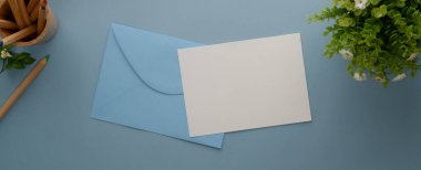 Açık mavi zemin üzerine dekore edilmiş sahte davetiye kartı, zarf, kart kağıdı ve dekorasyon