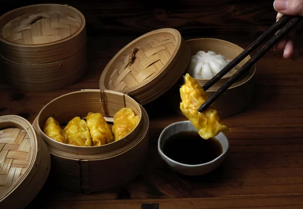 Close up view of female with chopstick ready to eat steamed dumplings serving on bamboo seamer in Chinese restaurants