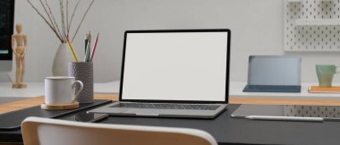 Model dizüstü bilgisayar, dijital tablet, akıllı telefon, kırtasiye malzemesi ve dekorasyonla ofis masasının kırpılmış görüntüsü. 