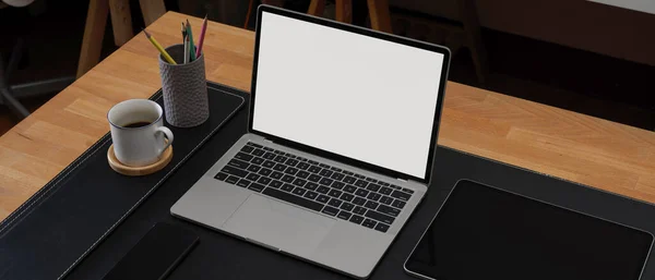 Cropped shot of modern workspace with mock-up laptop, stationery and coffee cup on wade table