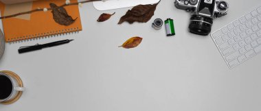 Fotokopi alanı, kamera, kırtasiye, kahve fincanı ve dekorasyonlu modaya uygun çalışma alanının üst görünümü
