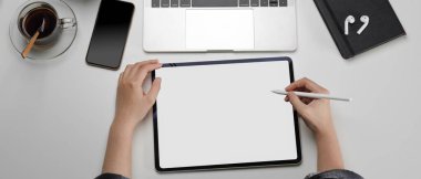 Basit bir çalışma alanında, tablet, akıllı telefon ve diğer malzemelerle çalışan kadınların genel görüntüsü.