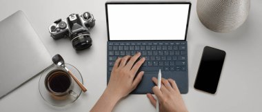 Basit bir çalışma alanında dijital tablet, akıllı telefon ve kamerayla çalışan kadınların genel görüntüsü. 