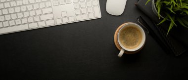 Fotokopi alanı, kahve fincanı, bilgisayar aygıtı ve dekorasyonu olan karanlık ofis masasının üst görünümü 