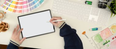 Kadın tasarımcının beyaz kalem ve boyama araçları ile çalışan stilus kalemle tablet üzerinde çalışmasının genel görünümü