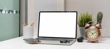 Bilgisayarı, akıllı telefonu, kulaklığı, kulaklığı ve süslemeleri beyaz masaya yerleştirin.