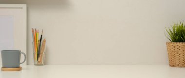 Fotokopi alanı, kırtasiye malzemesi, çerçeve, kahve fincanı ve beyaz masa süslemeleri olan modern çalışma masasının görünümünü kapat 