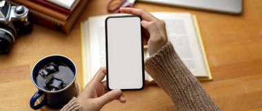 Çalışma masasında kitap ve kahve fincanı ile akıllı telefon kullanan kız öğrencinin görüntüsünü kapat. 