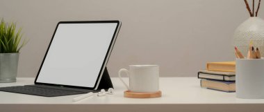 Kahve fincanı, kırtasiye ve dekorasyonla beyaz tablet üzerinde kesilmiş boş ekran görüntüsü.