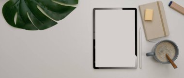 Tablet, kırtasiye malzemesi, kahve fincanı ve beyaz masadaki fotokopi alanı ile en küçük ofis masasının üst görünümü 