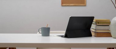 Sayısal tablet, kitap yığını, dekorasyon ve beyaz masadaki kopyalama alanı ile ev ofis masasının görünümünü kapat