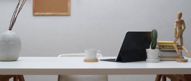 Ev ofis masasını laptopla, kitap yığınıyla, dekorasyonlarla ve beyaz masadaki kopyalama alanıyla kapat