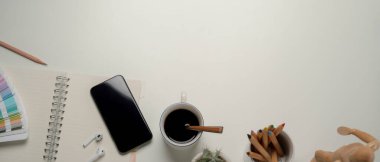 Kopya alanı, akıllı telefon, kırtasiye ve boyama araçlarıyla modern çalışma alanının üst görünümü