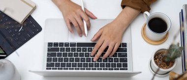 Dijital tabletli, malzemeli ve beyaz masadaki dekorasyonlu dizüstü bilgisayar kullanan kadınların el resimleri.