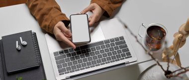 Ofis masasında ofis malzemeleriyle otururken, akıllı telefon kullanırken, kadınların yukarıdan çekilmiş görüntüleri..